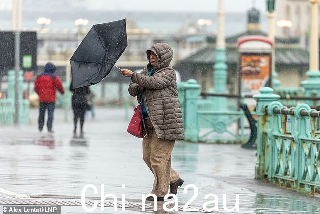 今天下午,在东萨塞克斯郡布莱顿的风中,一名公众打着伞在风雨中挣扎
