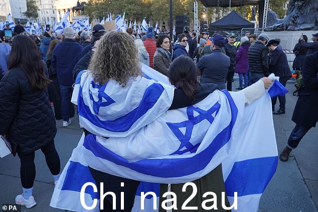 两名身披以色列国旗的妇女参加了在特拉法加广场举行的守夜活动,该活动突出了恐怖组织哈马斯人质和受害者的困境