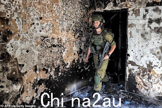 10 月 18 日,一名以色列陆军士兵在以色列南部卡法阿扎基布兹巡逻时走过一栋被烧毁的建筑