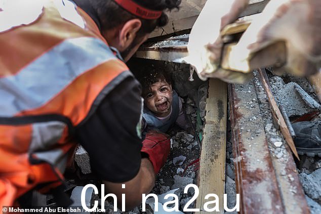 被困在瓦砾中,一名幼儿在加沙城一座被摧毁的建筑中被救出时哭泣