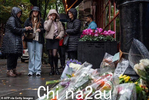 人们站在公寓楼外向演员马修·佩里致敬的鲜花前,这栋公寓楼被用作周日电视节目《纽约老友记》的外景镜头