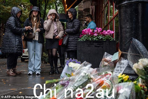 人们站在公寓楼外向演员马修·佩里致敬的鲜花前,公寓楼被用作2023 年 10 月 29 日在纽约拍摄的电视节目《老友记》的外景。54 岁的佩里因在广受欢迎的《老友记》中饰演俏皮的角色钱德勒·宾而闻名于世,该剧从 2023 年 10 月开始播出了 10 季。 1994 年至 2004 年。执法部门消息人士告诉《洛杉矶时报》,10 月 28 日,急救人员在佩里家中的热水浴缸中发现昏迷不醒,但无法使他苏醒。警方证实,他们已对“一名 50 多岁男性的死亡进行调查”。 (亚当·格雷/法新社拍摄)(亚当·格雷/法新社通过盖蒂图片社拍摄)