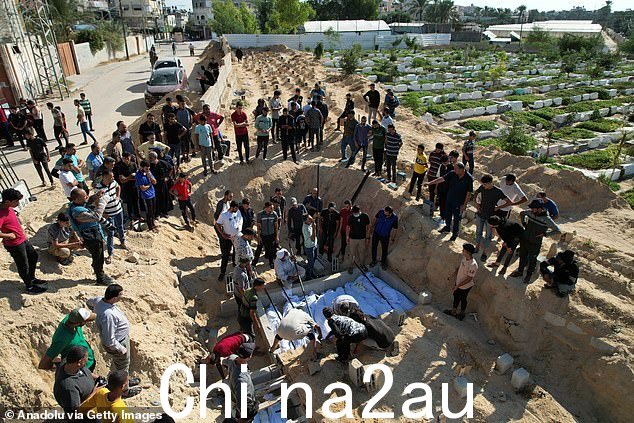 周一在加沙代尔巴拉赫的万人坑中埋葬在以色列袭击中丧生的巴勒斯坦家庭尸体的鸟瞰图