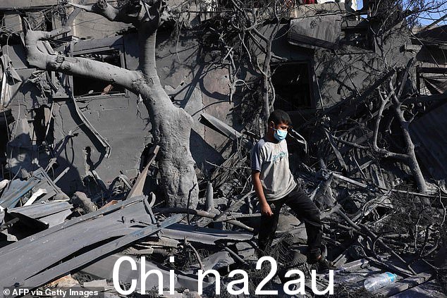 以色列周二在加沙地带南部拉法实施轰炸后,一名青年走在建筑物的废墟上