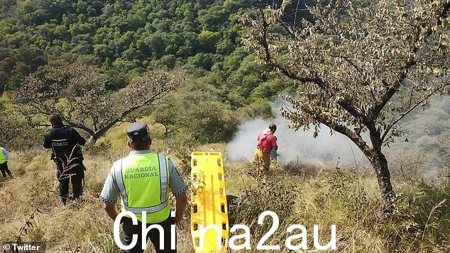消防队员以及国民警卫队和海军成员站在坠机地点附近,一架里尔喷气式飞机坠毁,所有四名机组人员丧生,其中包括一名医生