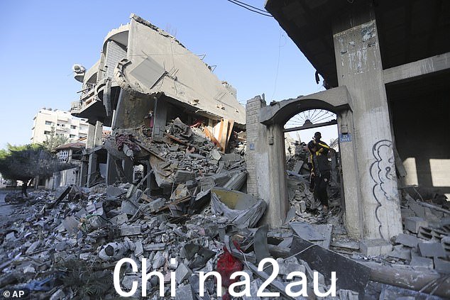 巴勒斯坦人走过在以色列轰炸拉法加沙地带被摧毁的建筑物