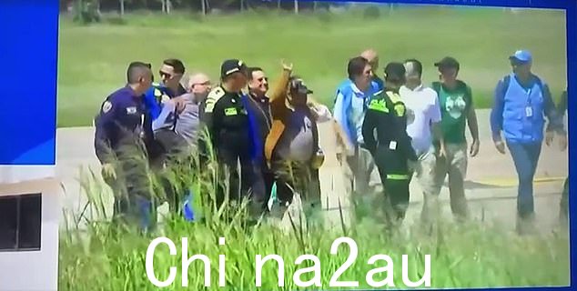 足球运动员的父亲(照片中穿着棕色外套)在被护送到安全地点时挥手
