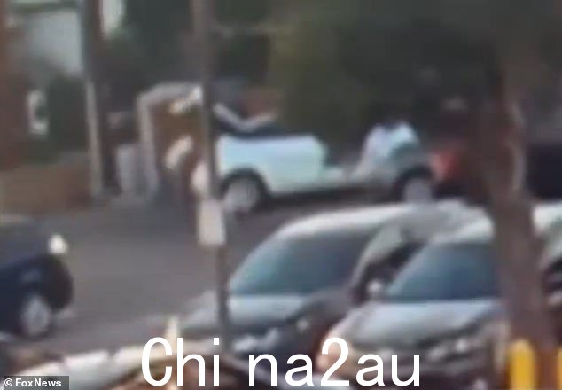 可以看到该男子正在努力从车后部抬起沉重的黑色物体