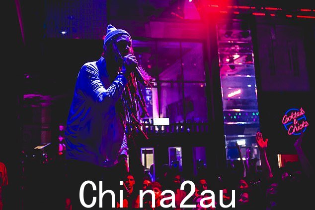 Gym Class Heroes 主唱身穿长袖白衬衫和亮绿色短裤,头戴灰色无檐小便帽,引人注目