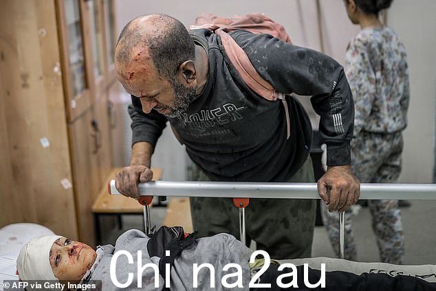以色列周三在加沙地带南部轰炸汗尤尼斯后,一名受伤的巴勒斯坦男子看着医院轮床上躺着的受伤儿童