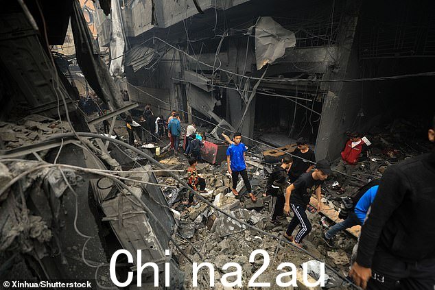 星期三,人们在以色列空袭加沙地带南部城市汗尤尼斯的建筑物废墟中看到人们