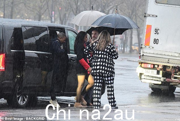 盛大出口:她先退出,周围多人打着雨伞,然后 Leodis 被交给她