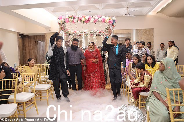 当这对夫妇走在客人手持的鲜花下时,烟雾充满了地板