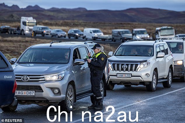 一名警察正在检查正在车里等待回家的格林达维克当地居民