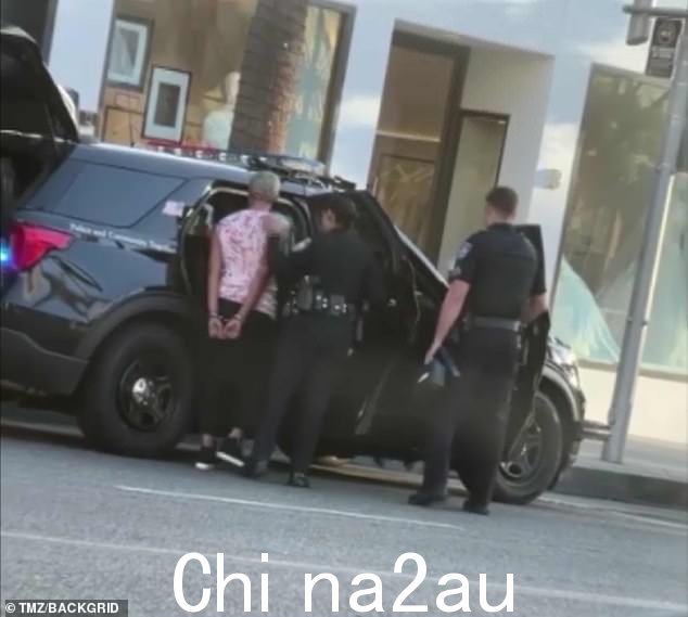 戴上手铐:她转向警车,显示她在被两名警官带领之前被戴上手铐