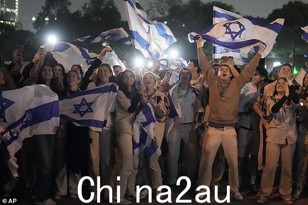 一群以色列人庆祝一架载有加沙地带人质的直升机降落在以色列佩塔提克瓦施耐德儿童医疗中心的直升机停机坪上