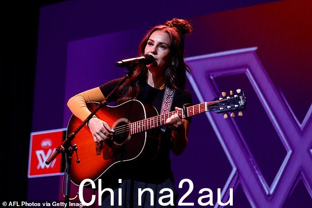 当她走上舞台时,她穿着海军蓝裙子和长袖黄色衬衫,里面是黑色 T 恤。