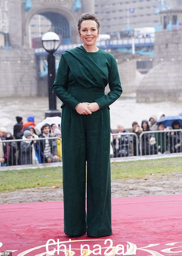 华丽:周一,奥利维亚·科尔曼 (Olivia Colman) 与搭档在伦敦标志性塔桥为旺卡 (Wonka) 拍照,身着深绿色连身裤,展现出别致的身材