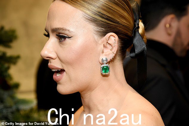 Scarlett accessorized with a pair of dangling, diamond-encrusted white gold earrings featuring a massive emerald.