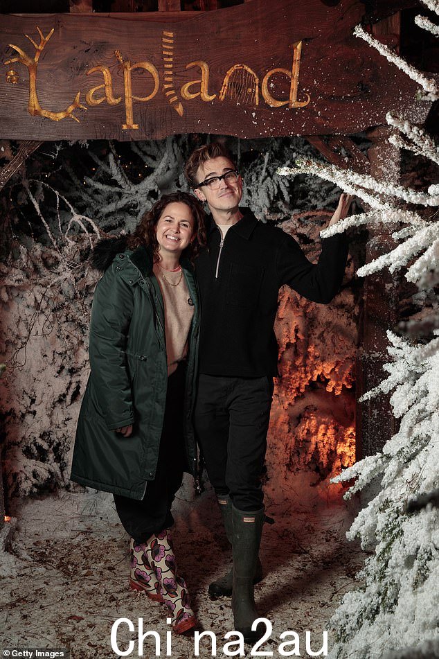 乔凡娜·弗莱彻 (Giovanna Fletcher) 穿着米色套头衫和黑色长裤,与丈夫汤姆 (Tom) 合影,身材休闲,