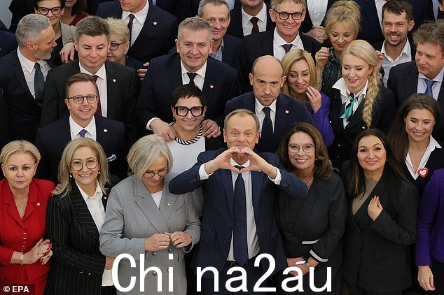 公民平台党领袖唐纳德·图斯克 (Donald Tusk)(中)在众议院与公民联盟 (KO) 成员合影留念时用手形成一颗心