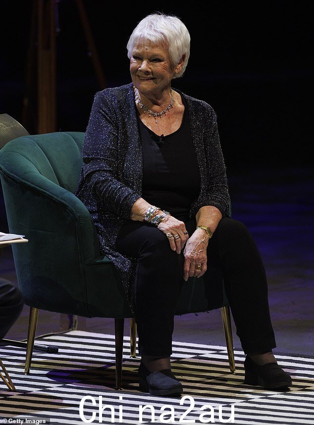 Dame Judi 身穿黑色套装,搭配披在肩上的时尚长开衫,看起来很帅气