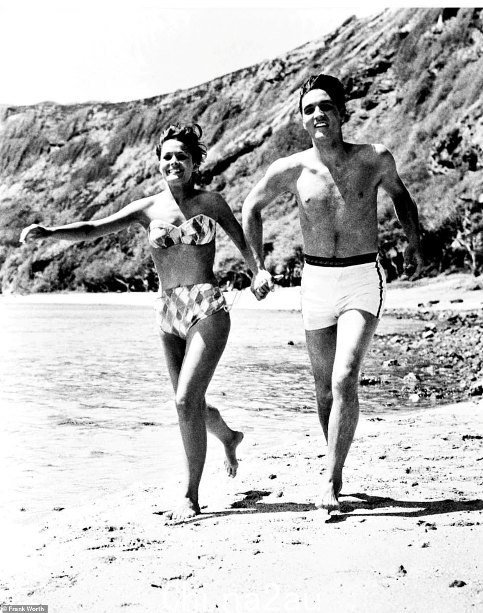埃尔维斯·普雷斯利 (Elvis Presley) 和联合主演琼·布莱克曼 (Joan Blackman) 在 1963 年音乐剧《蓝色夏威夷》片场时手牵手在海滩上奔跑的照片。这位歌手非常喜欢夏威夷,因此在热带岛屿上拍摄了三部电影“class =