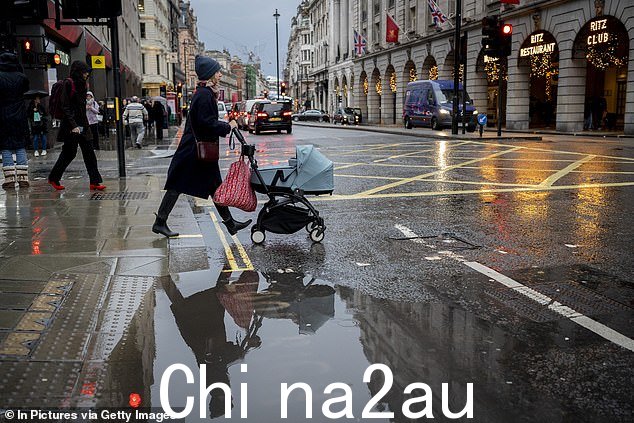 一个女人推12 月 12 日一个下雨的下午,一个孩子坐在婴儿车里穿越皮卡迪利大街