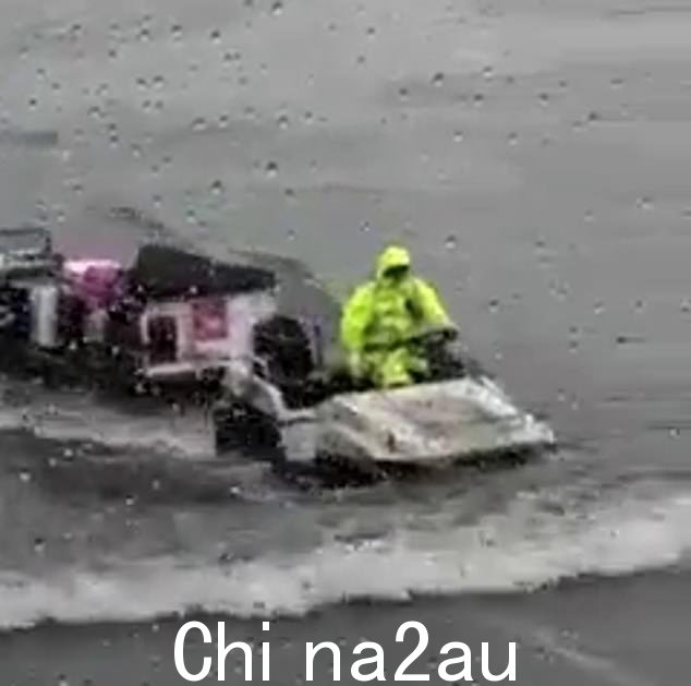 周日,一名行李搬运工试图在悉尼机场的大雨中前行
