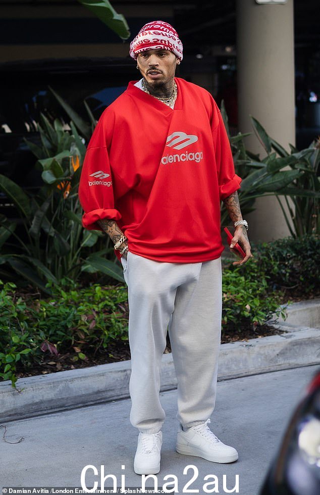 Chris 穿着一件红色超大 Balenciaga T 恤,搭配灰色慢跑裤、一双白色 Nike Air Force 运动鞋和几条链条