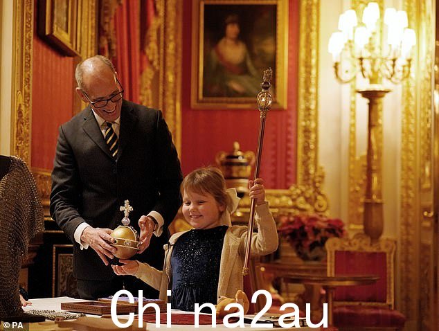 温莎城堡管理员邓肯·杜瓦 (Duncan Dewar) 向七岁的奥利维亚·泰勒 (Olivia Taylor) 提供加冕球和权杖的复制品,她开心地笑着