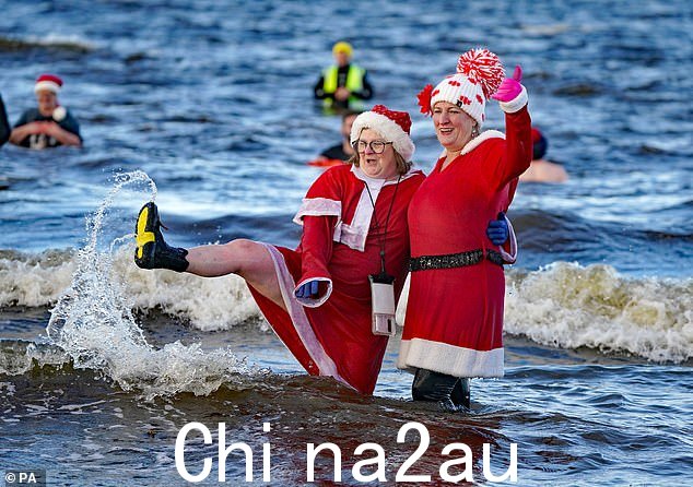 身着圣诞老人服装的女士们在艾尔郡艾尔海滩参加浸水活动