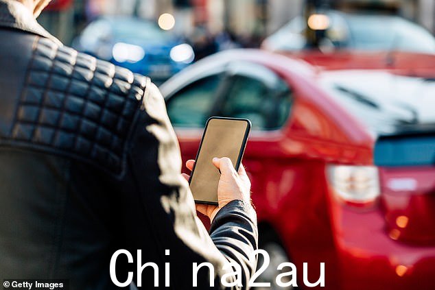 该停车应用估计在英国拥有约 1700 万用户。如图:一名男子在停车场手持智能手机的文件图像