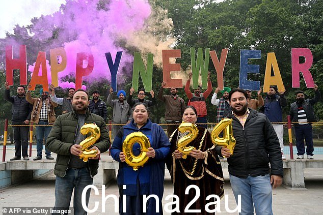 印度:旁遮普邦阿姆利则的当地人将在英国时间晚上 9.30 庆祝新年,他们拿着字母和气球摆姿势