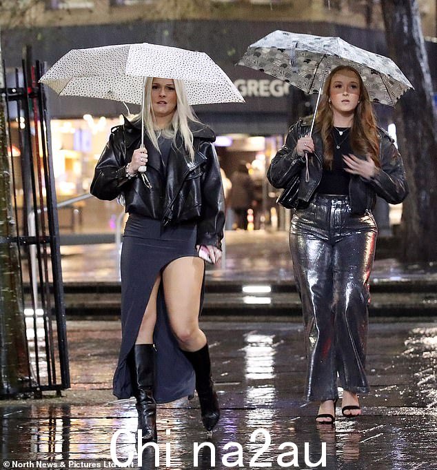 NEWCASTLE:一对准备充分的狂欢者高举雨伞穿过纽卡斯尔市中心