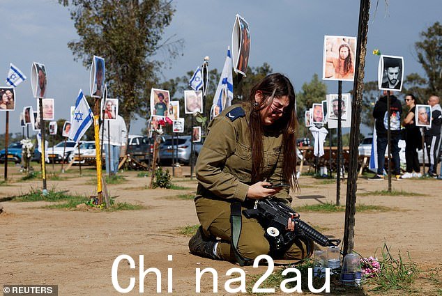 在激动人心的追悼会上,一名年轻的以色列士兵悲痛欲绝,瘫倒在地,跪在她的亲戚 Tair 和 Hodaya David 的照片前,她们是被杀害的两姐妹。当他们试图这样做时被杀逃离节日