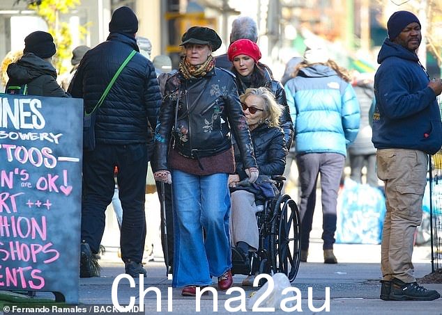 萨兰登,77 岁,穿着牛仔裤和印有花朵的黑色机车夹克,友善地走在她身边