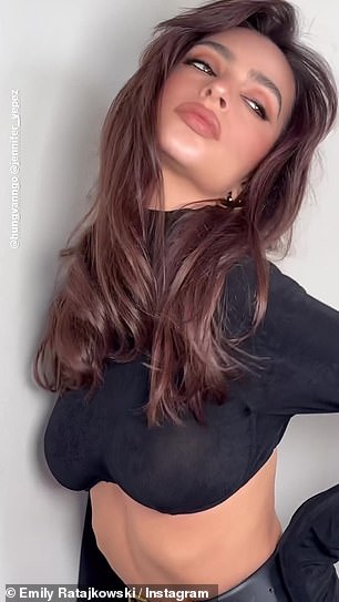 Emily 穿着黑色短款高领毛衣和配套的束带铅笔裙,炫耀她绷紧的躯干