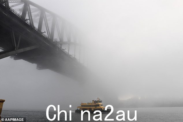 照片中一艘渡轮穿过雾气从悉尼海港大桥下经过