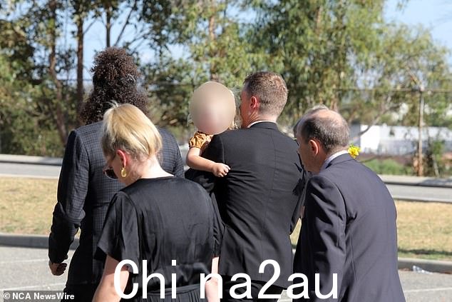 丹尼斯把他的小女儿抱出部队,女儿从棺材里抓起一朵向日葵