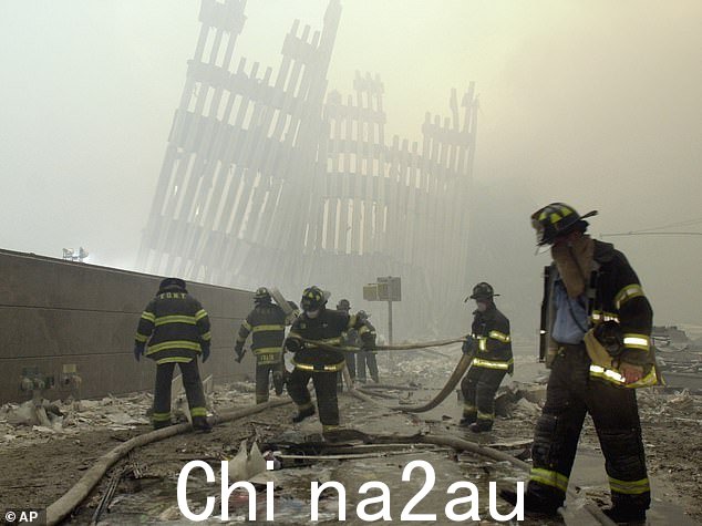 9/11 恐怖袭击后,消防员在被毁坏的竖框下工作,这些垂直支柱曾经面向世贸中心塔楼高耸的外墙