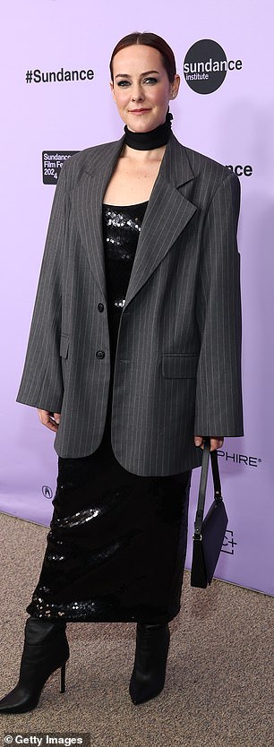 她将一件灰色细条纹西装外套分层穿在衣服上,她选择将前面的扣子解开