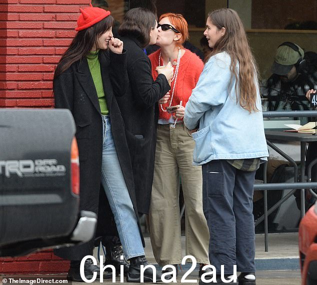 她佩戴了一条长长的珍珠项链和别致的太阳镜,她染成鲜艳的红色头发与她外套的颜色搭配得很好