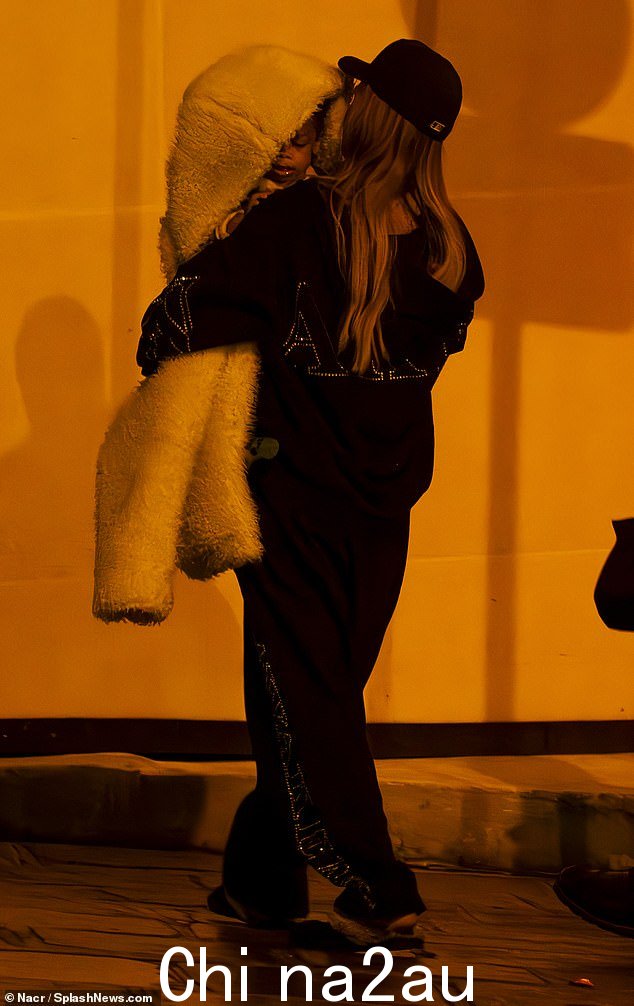 蕾哈娜 (Rihanna) 身穿黑色和银色运动服,休闲身材,并戴着深色帽子来完成造型