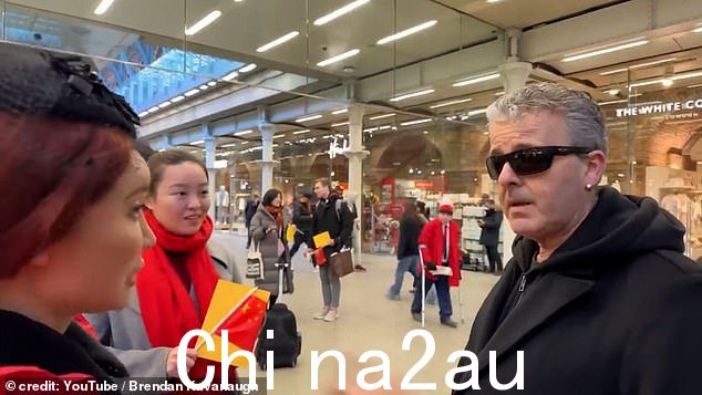 戴着红领巾的游客聚集在钢琴家周围,钢琴家一再向他们解释,因为是在公共场所,所以可以拍摄。 “我们在英国,我们不在中国,”他补充道。” class=