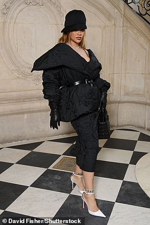 蕾哈娜 (Rihanna) 穿着白色高跟鞋提高了身高,并在镜头前微笑