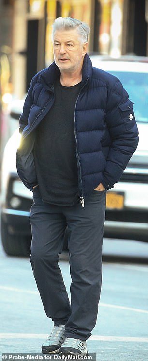 他还穿着黑色 T 恤、裤子和灰色运动鞋
