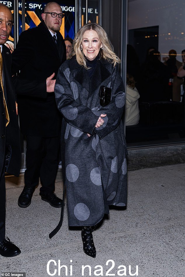 凯瑟琳·奥哈拉 (Catherine O'Hara) 离开放映厅时,穿着斑点长外套和镶钉高跟靴。