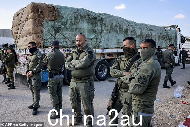 以色列军队士兵站在一辆向加沙地带运送人道主义援助物资的埃及卡车旁