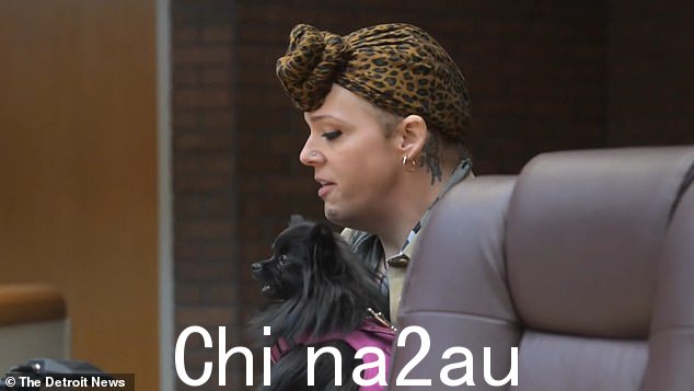 金斯利在周三的刑事诉讼中抓着一只黑色的小安慰犬
